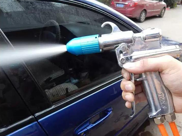 A man is washing a car with a high pressure washer gun.