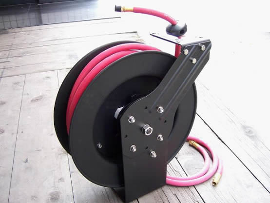Retractable hose reel in black color with pink hose on the ground